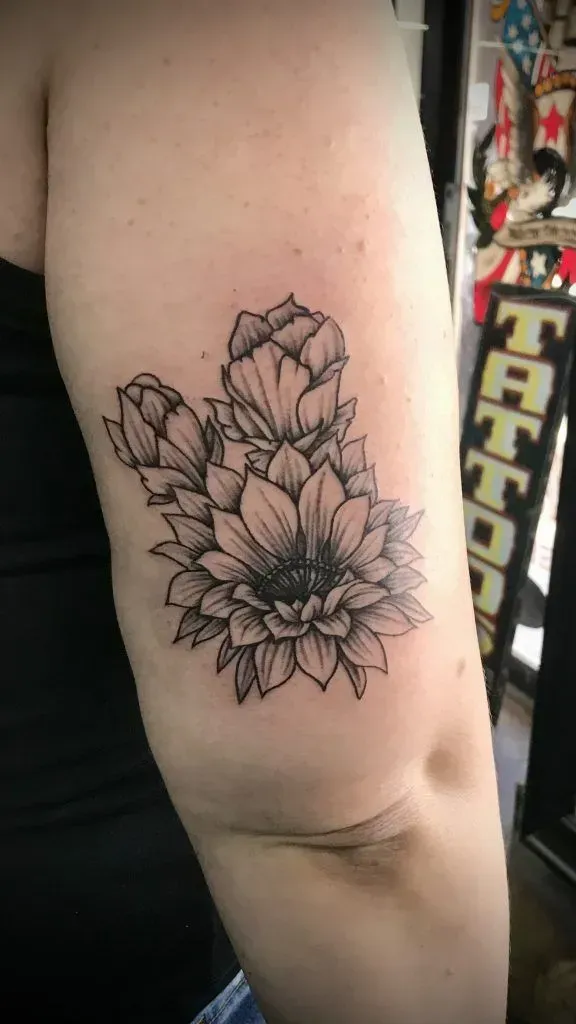 Black and white floral tattoo on an arm, with a partial view of a tattoo shop.