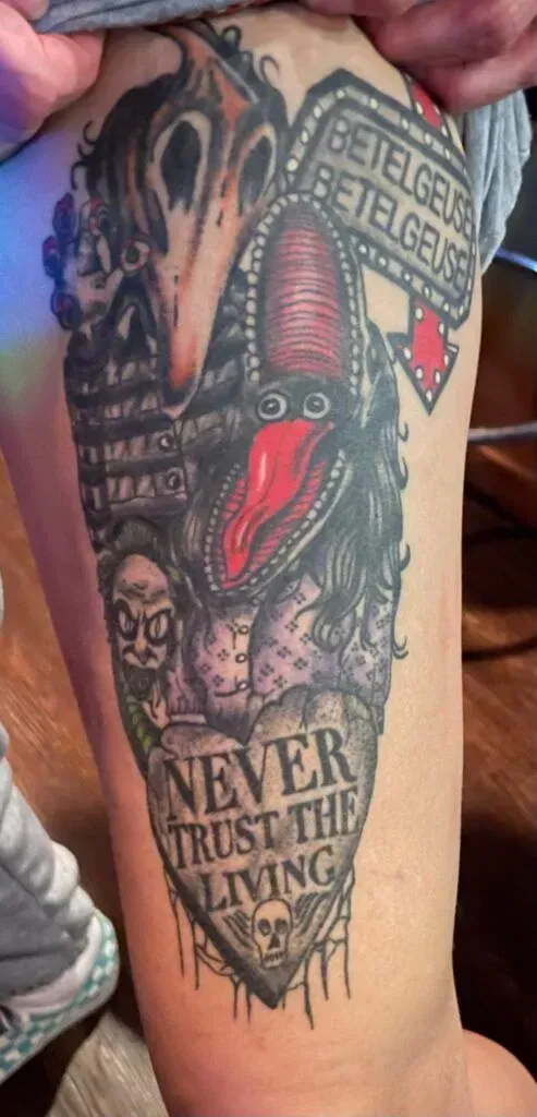 Beetlejuice tattoo on a leg featuring the character's face, a tombstone reading