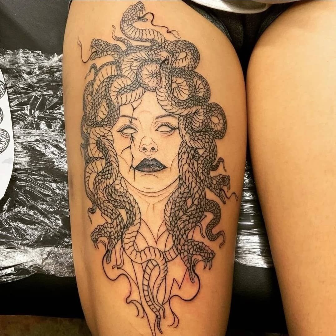 A woman has a medusa tattoo on her thigh