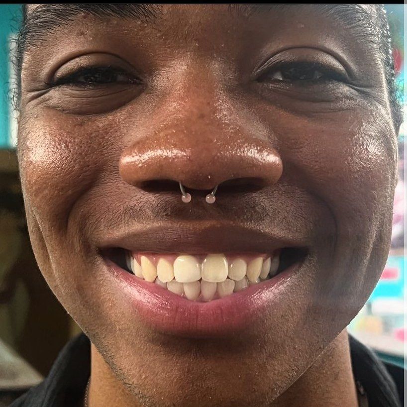 A close up of a man 's face with a nose ring