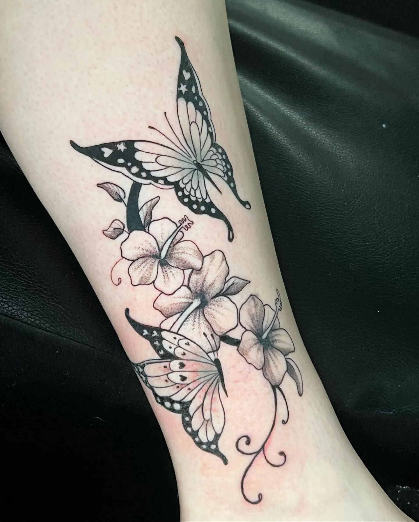 Black butterfly and white flower tattoo on a wrist/forearm.
