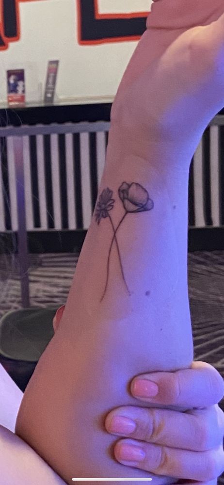 A woman has a tattoo of two flowers on her wrist.