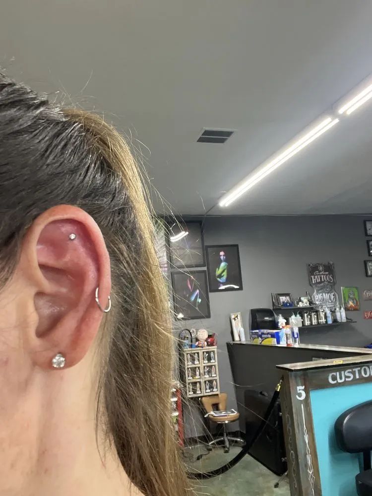 Close-up of an ear with multiple piercings in a tattoo shop interior