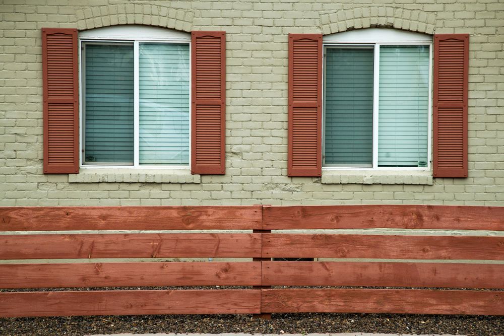 A Brick Building With Red Shutters And A Wooden Fence — Smith Aluminium In Warners Bay, NSW
