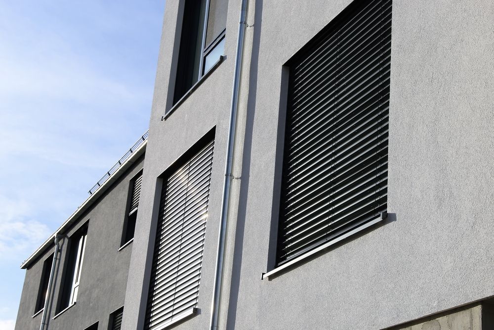 A Grey Building With Black Shutters On The Windows — Smith Aluminium In New Lambton, NSW