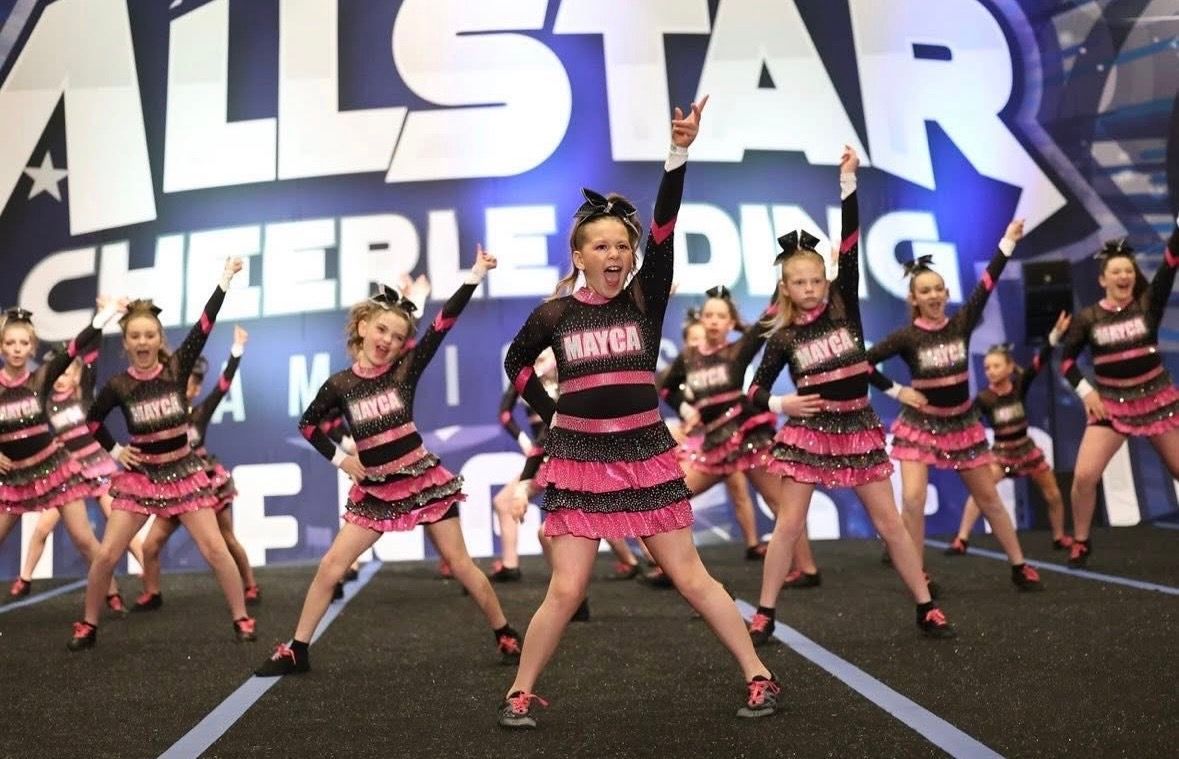 Cheerleaders in pink and black uniforms performing at an 