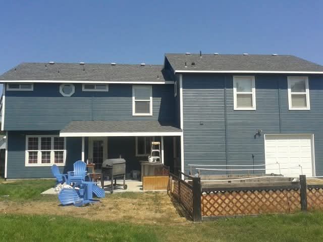Exterior painting job of a blue house with a white garage door