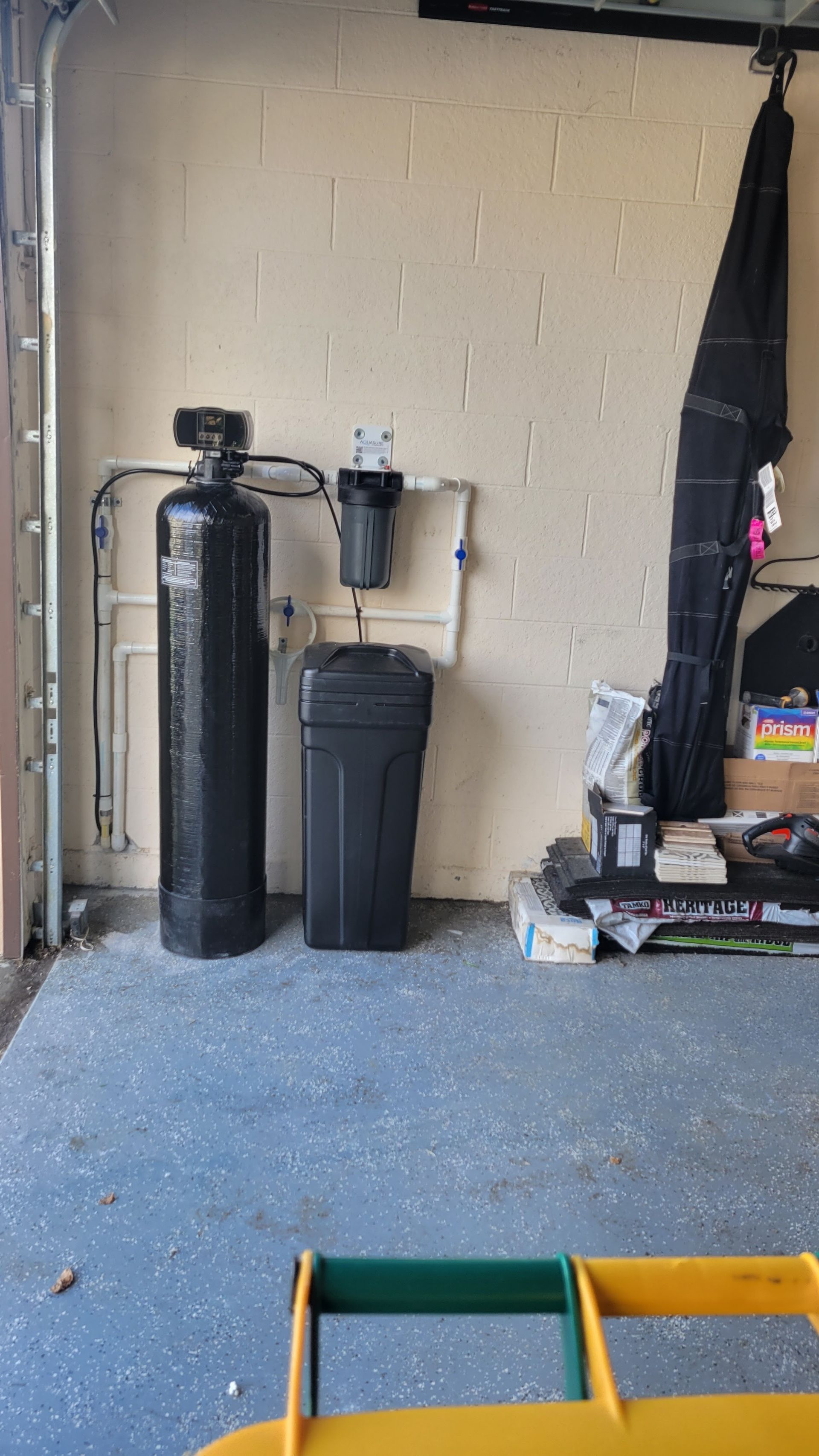 A garage with a water filter and a trash can.