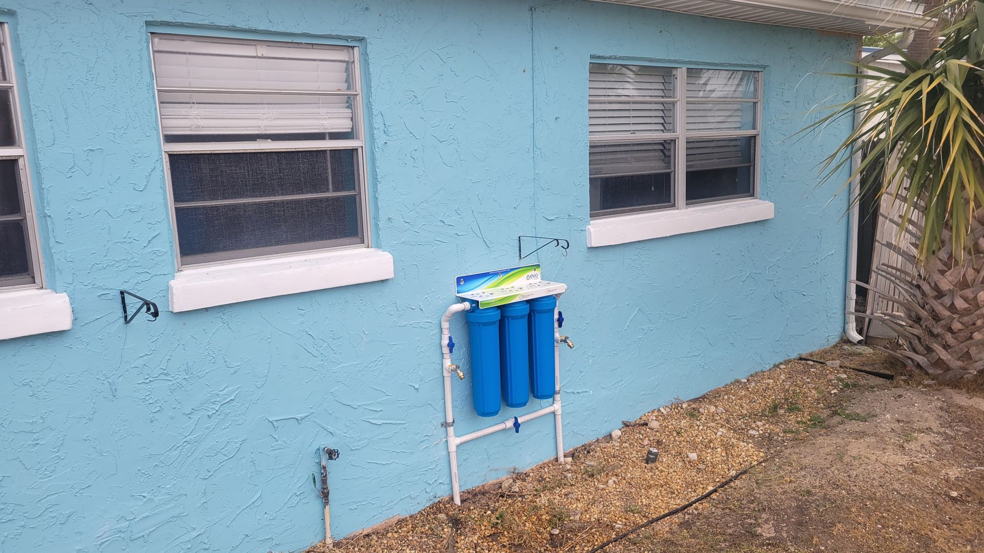 A blue house with a water filter on the side of it.