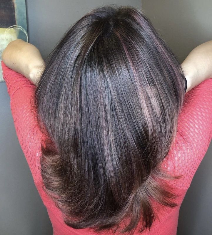 Back view of a person with straight, dark brown hair with subtle reddish-brown highlights, wearing a coral top.