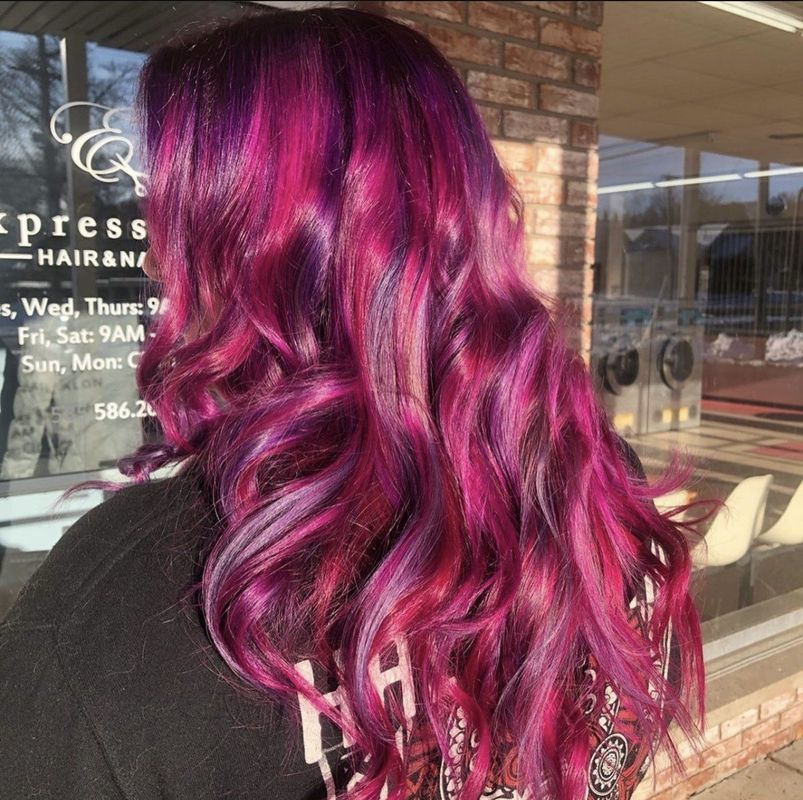 Long, wavy hair colored in vibrant, blended shades of magenta, violet, and deep pink, viewed from behind.