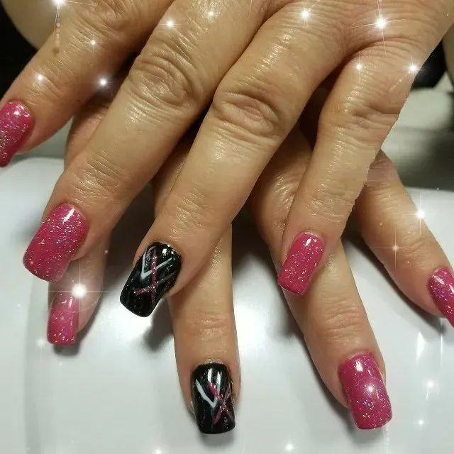 Manicured nails featuring alternating vibrant pink glitter polish and black nails with white and pink cross designs.