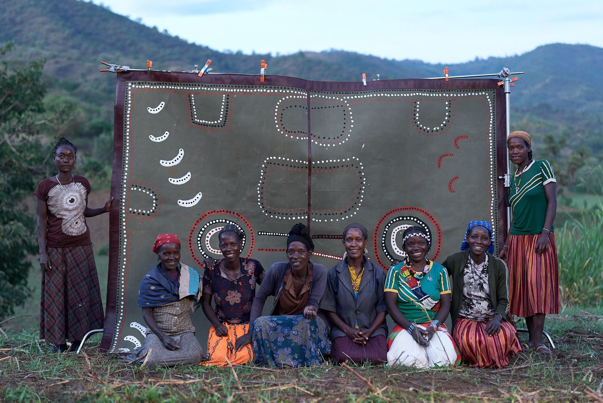 The Ari people are posing for a picture in front of their Artwork.