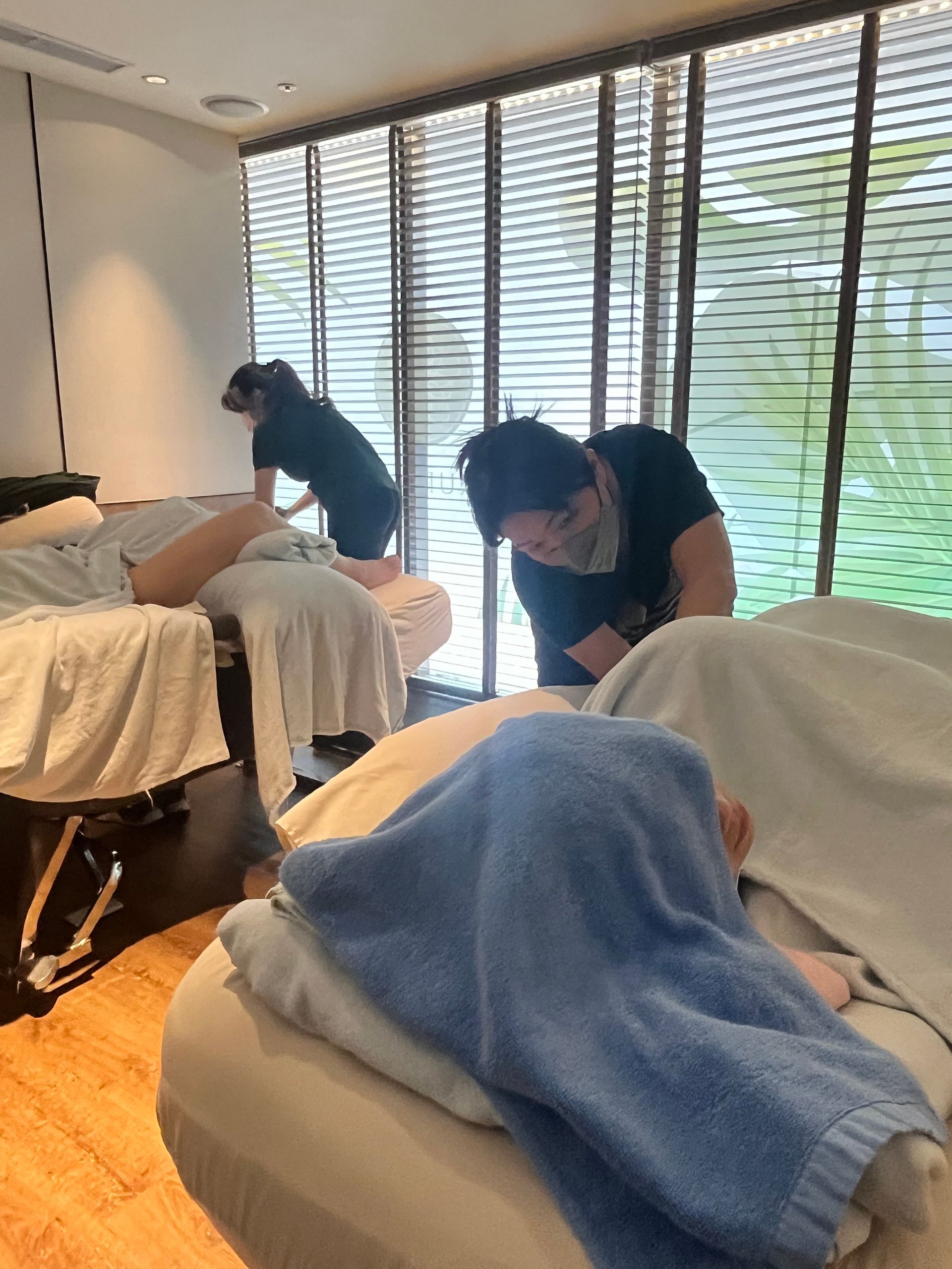 按摩理療師在設有三張按摩床和百葉窗的水療中心提供按摩服務。