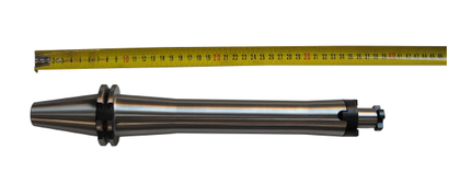 Ein gelbes Maßband über einem glänzenden, zylindrischen Metallwerkzeug mit schwarzem, konischem Ende