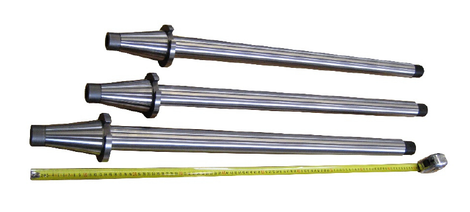 Three metal industrial nozzles with black tapered ends and a yellow measuring tape below them on a white background