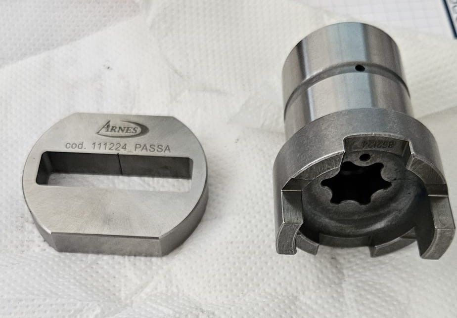 Zwei silberne Metallteile für industrielle Anwendungen, eines mit einem weißen Etikett und eines mit einer sternförmigen Innenseite.