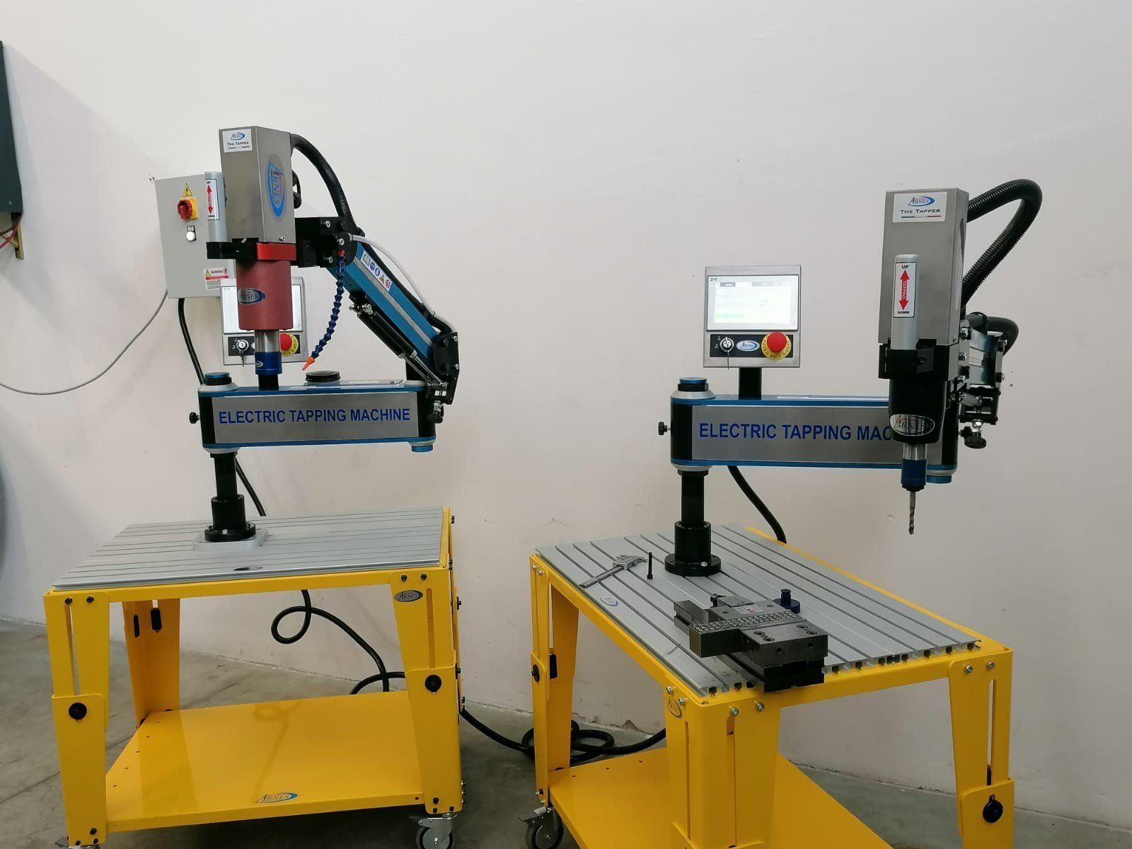 Due macchine CNC da tavolo su tavoli gialli in una stanza simile a un'officina.