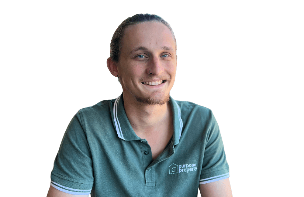 Man with light skin and a ponytail smiles wearing a green polo shirt.