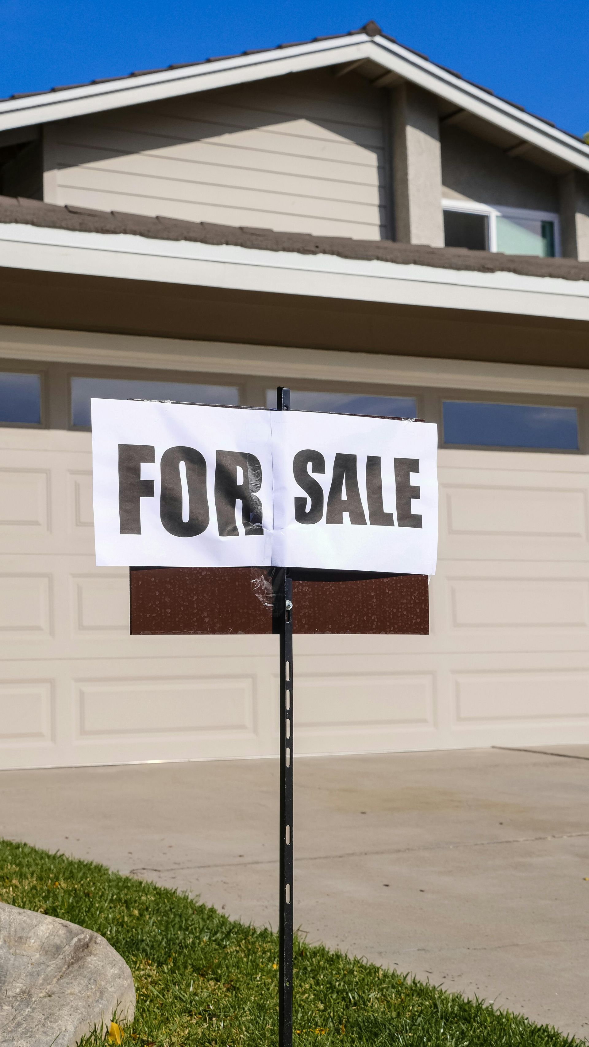 A house with a sign for sale infront.