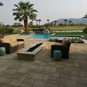 Outdoor patio with wicker furniture, a stone fire pit, and swimming pool overlooking a golf course and mountains.