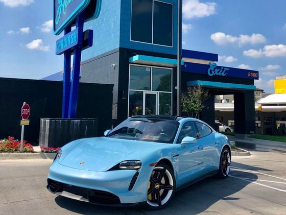 Light blue Porsche in front of a blue car wash building with Hello Deluxe Car Wah signage in Denver, Colorado