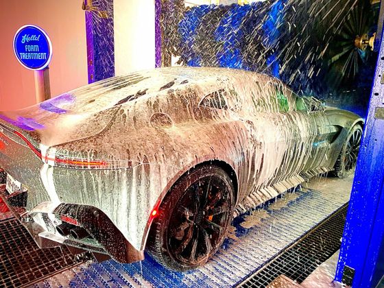 Silver sports car covered in foamy soap at a Hello Deluxe car wash in Dallas,Texas.