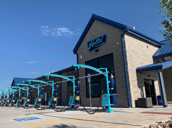 Exterior of a teal and blue car wash building under a clear sky in Dallas, Texas