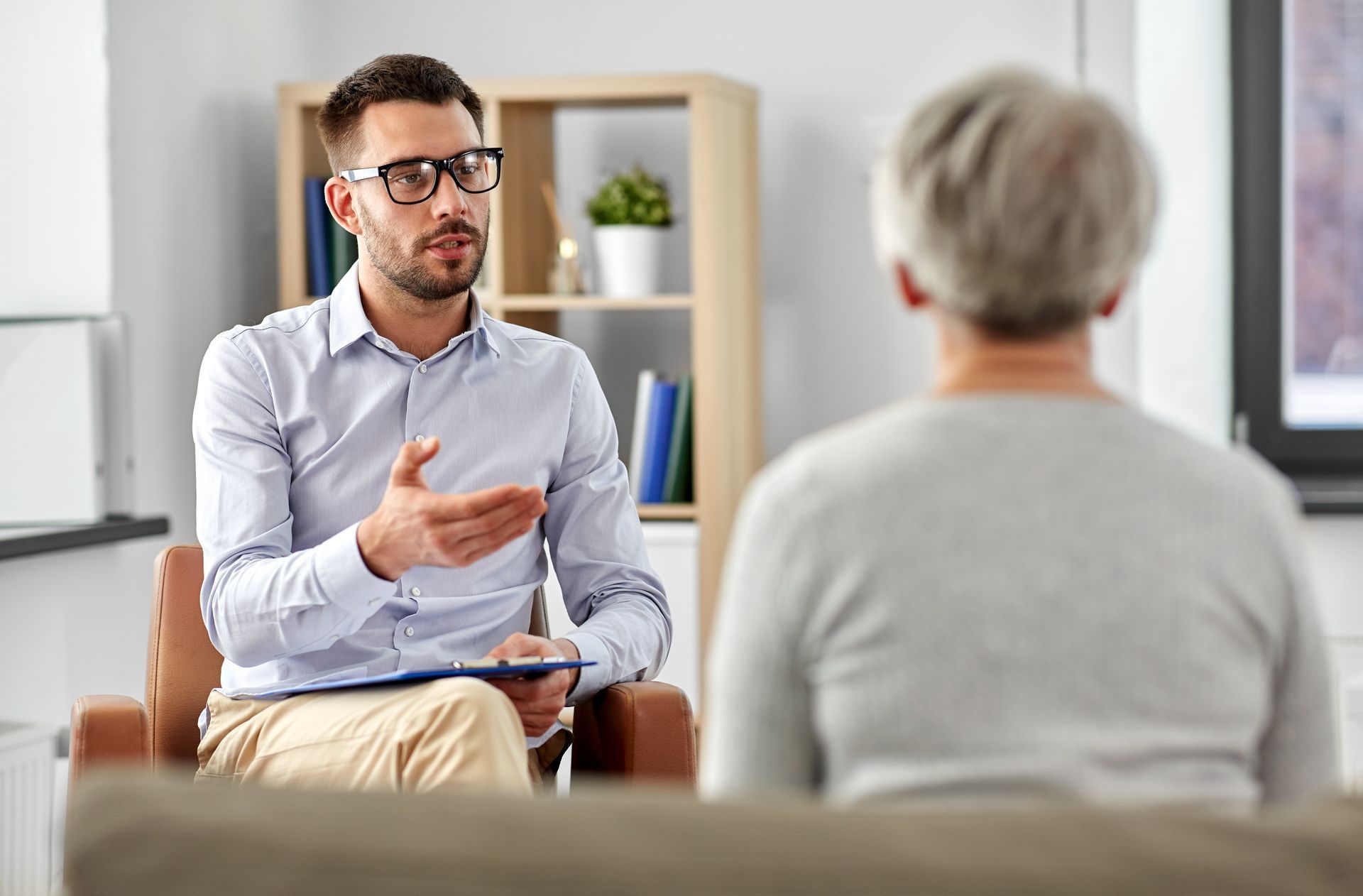 A man is sitting in a chair talking to an older woman.