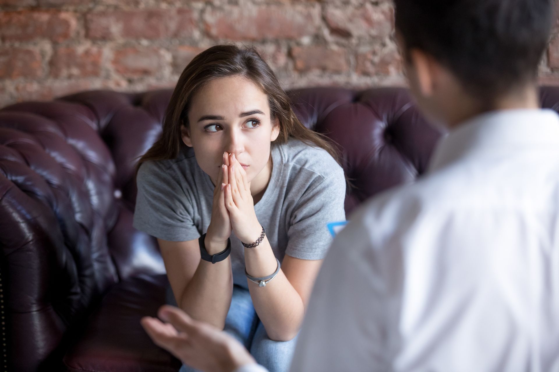 A woman is sitting on a couch talking to a man.