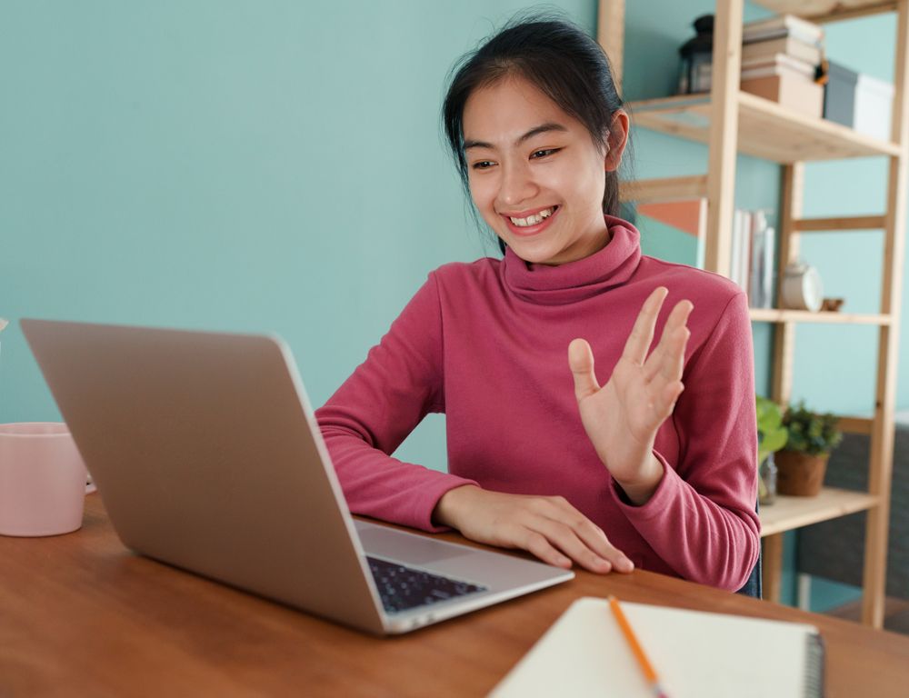 A woman is sitting at a desk using a laptop computer.