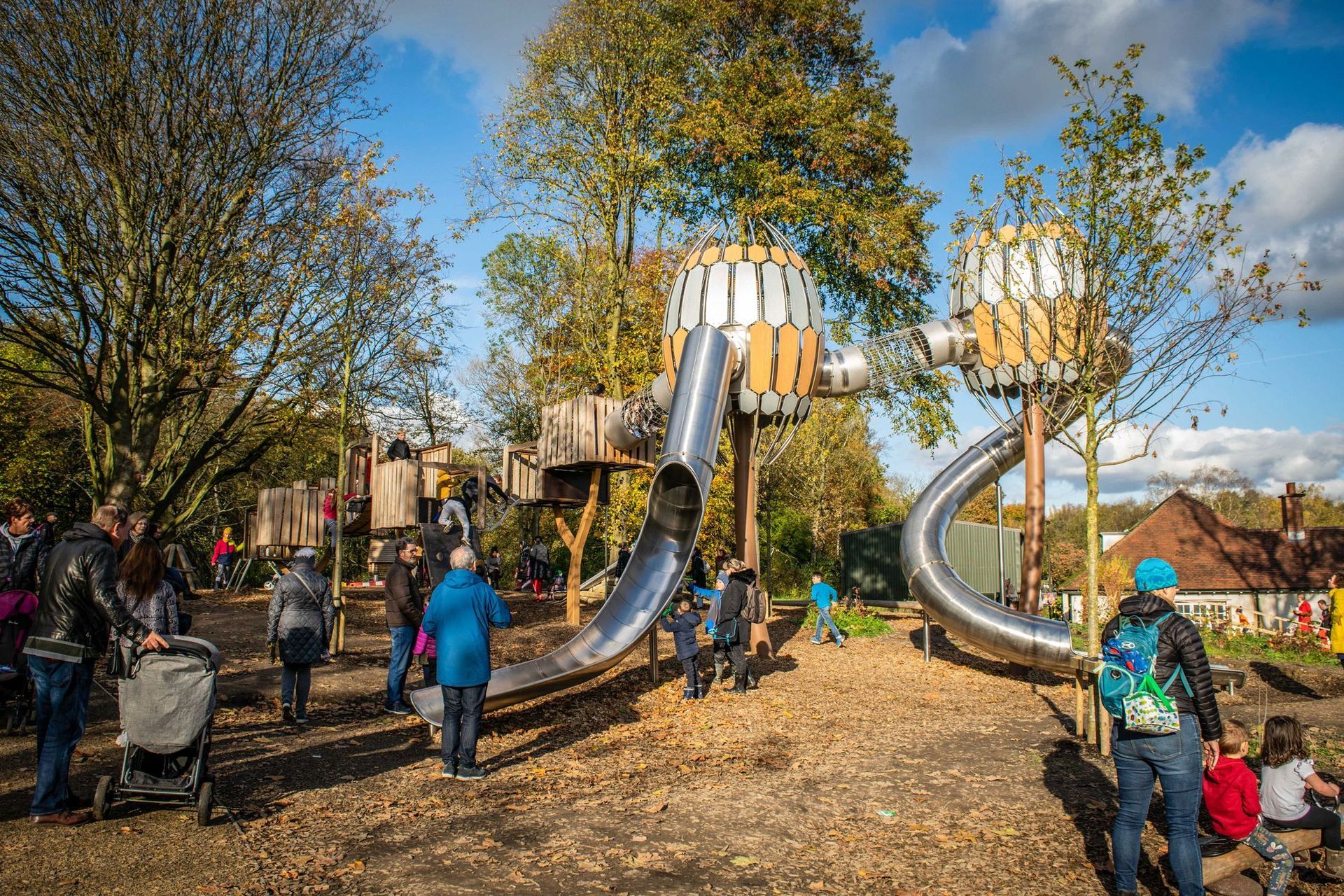 Children playing on swings and a playground with trees and stones, outdoors.