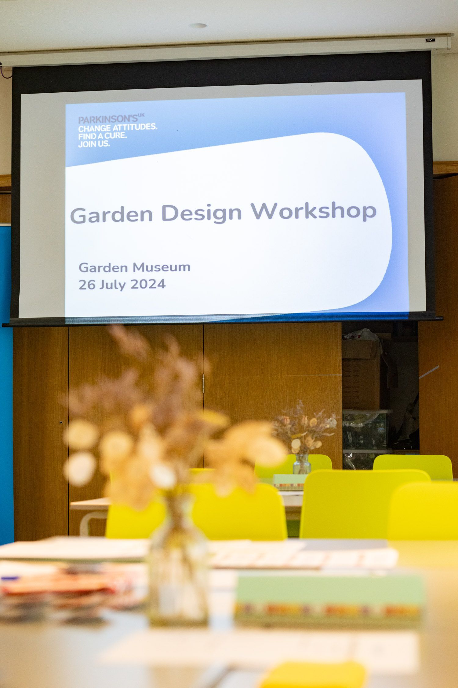 People examining designs at a table, one pointing to a blue logo, likely brainstorming.