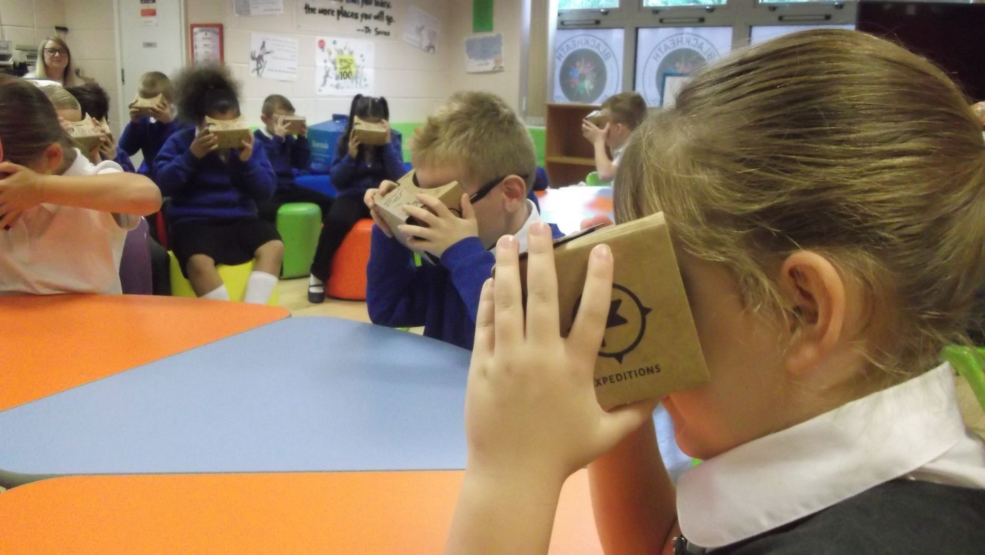 Schoolchildren using cardboard virtual reality viewers in a classroom setting.