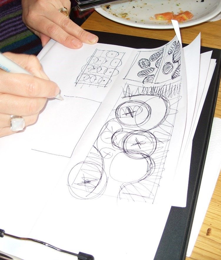 Person sketching on paper, revealing a design of various objects.