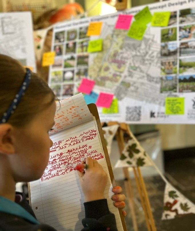 Girl writing in notepad with board covered in post-its and map in the background.