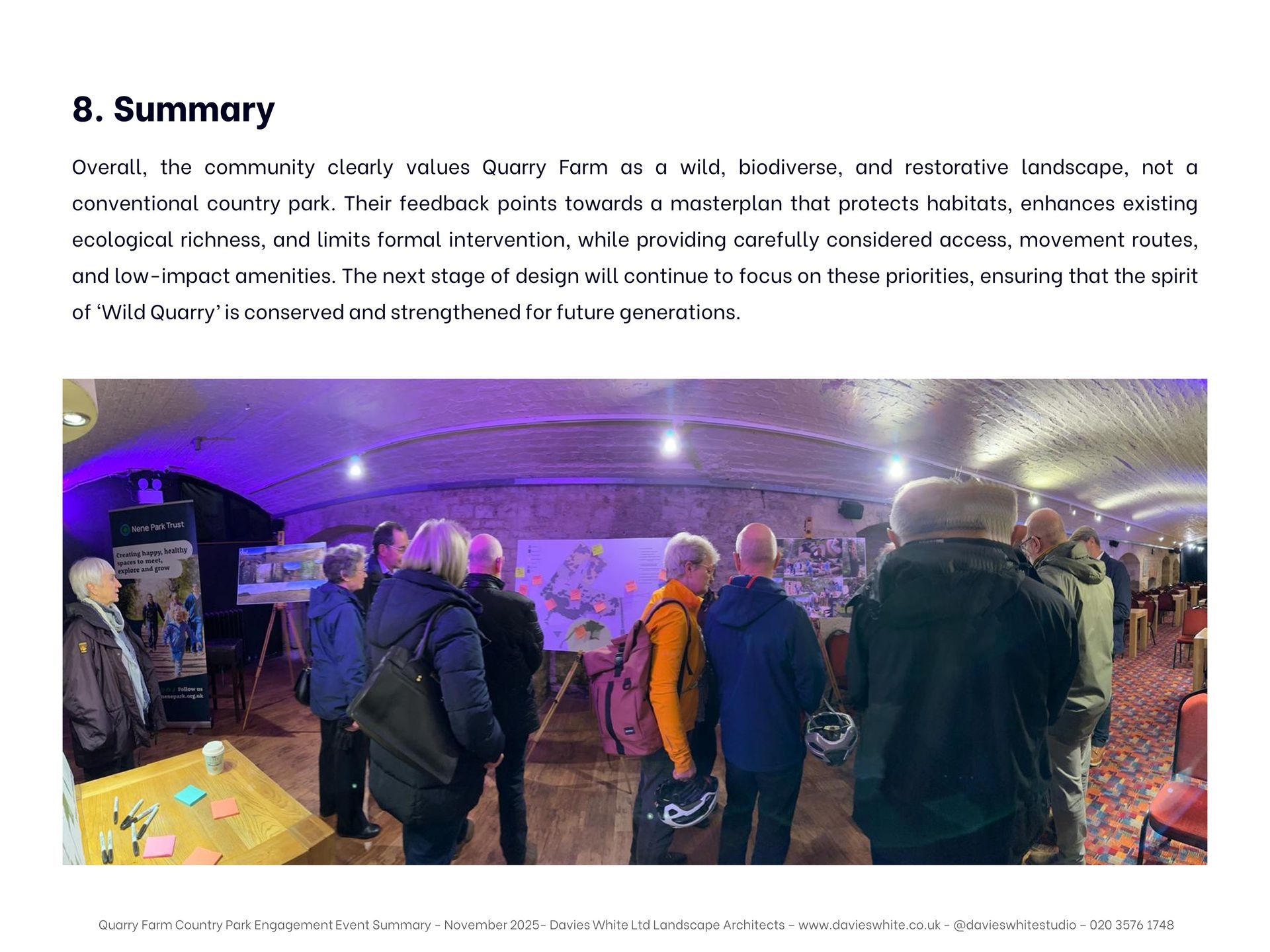 A group of people standing in an arched, stone-walled room, looking at displays and maps during an indoor event.