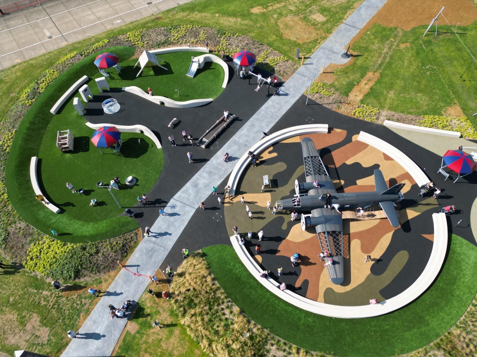 Overhead view of a park with a plane display. Circular areas: one with playground, the other with a camouflaged plane.