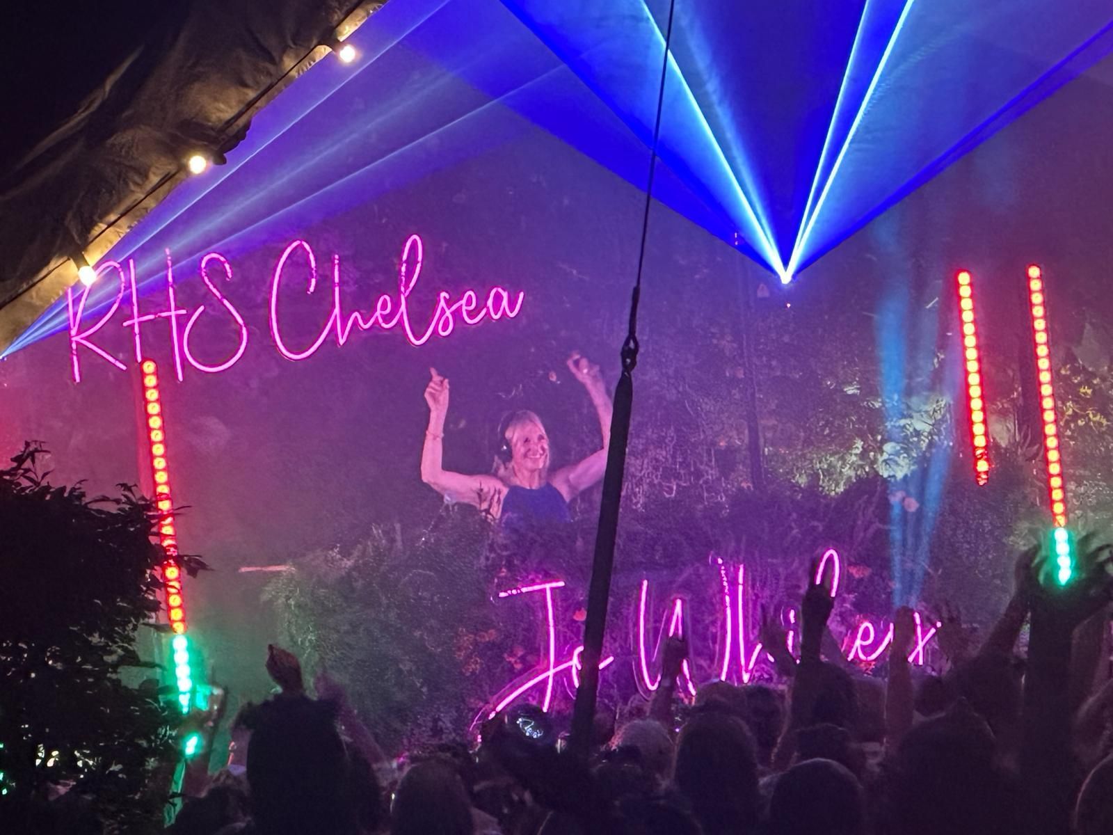 Chelsea Late with JO Whiley - Neon-lit concert stage with pink and blue lasers, a performer, and cheering crowd under smoke