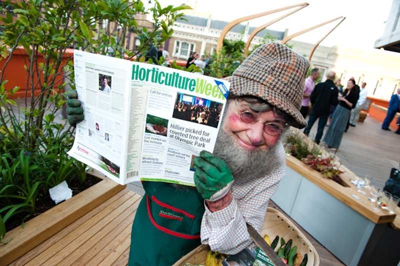Smiling gardener in costume reading