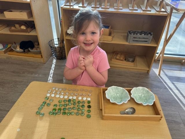 Smiling child at a table with the cards and counters material in a classroom setting