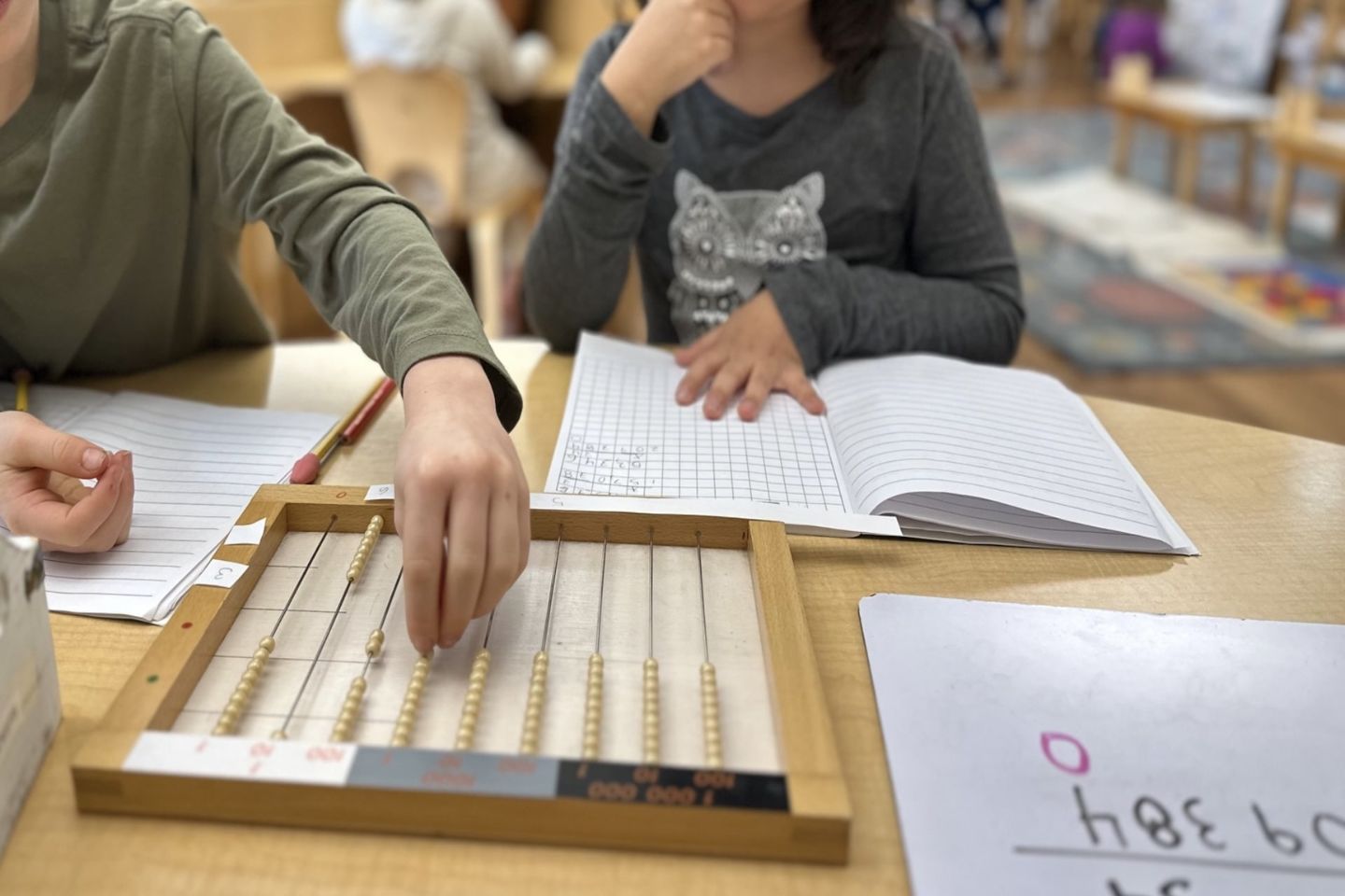 Child using Montessori Flat Bead Frame to explore large-number multiplication through hands-on math.
