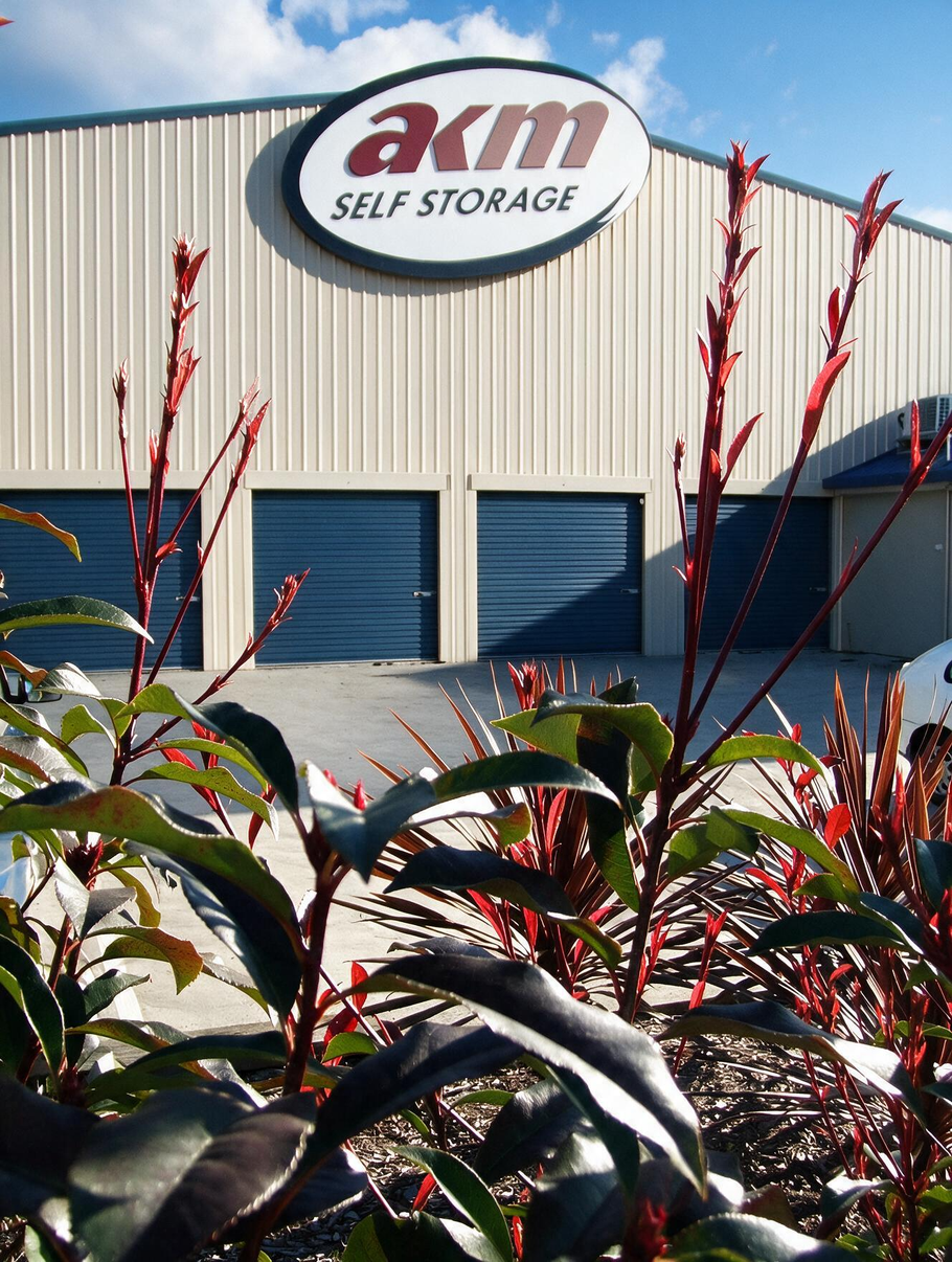 Partially open blue metal roll-up door revealing an empty storage unit corridor