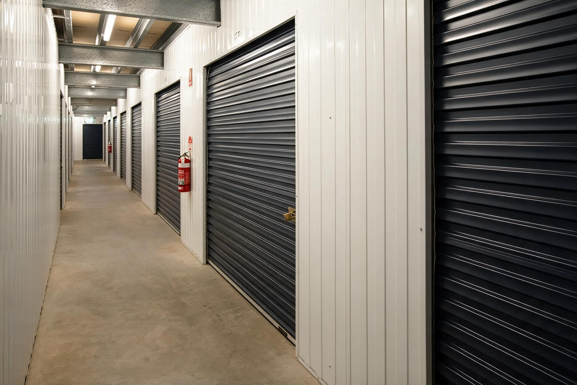 Indoor storage hallway with closed unit doors and a fire extinguisher on the wall