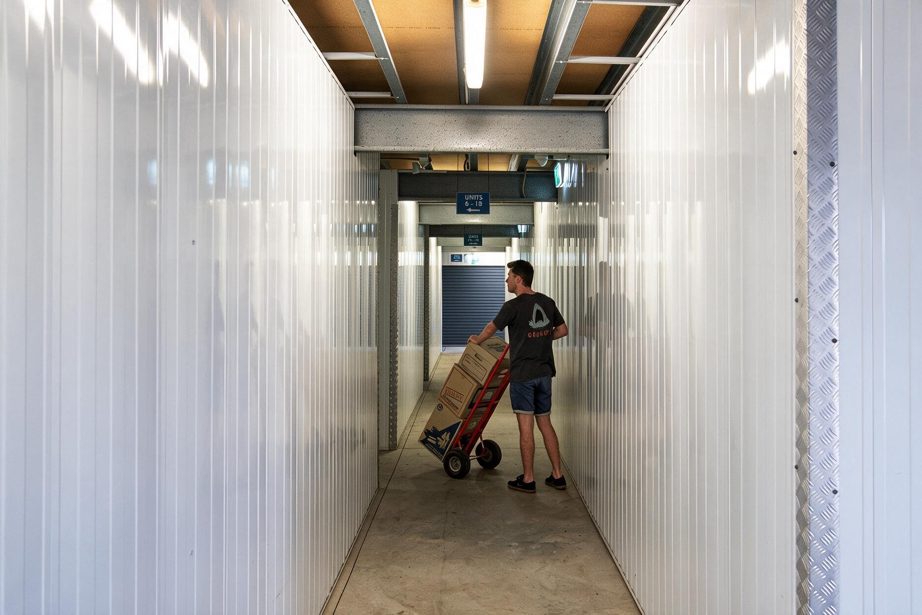 Person pushing a cart down a narrow white hallway