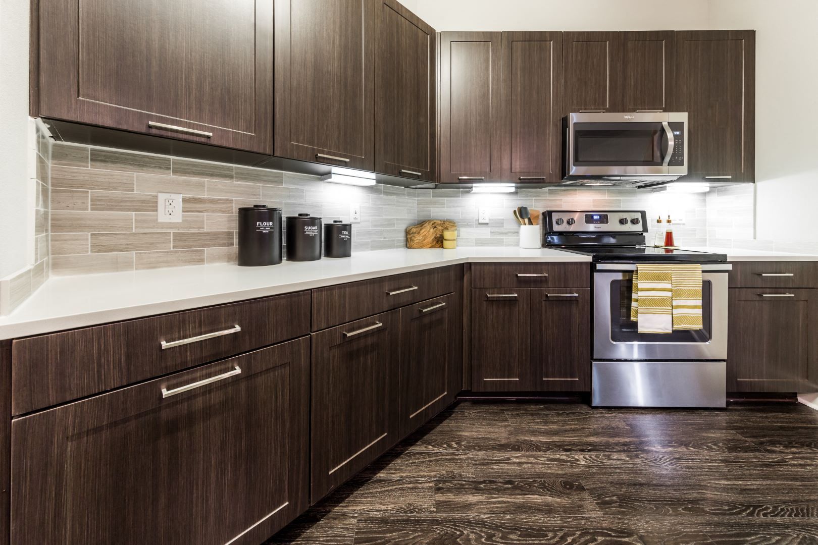 Modern kitchen with dark wood cabinets, stainless steel appliances, and dark hardwood floors