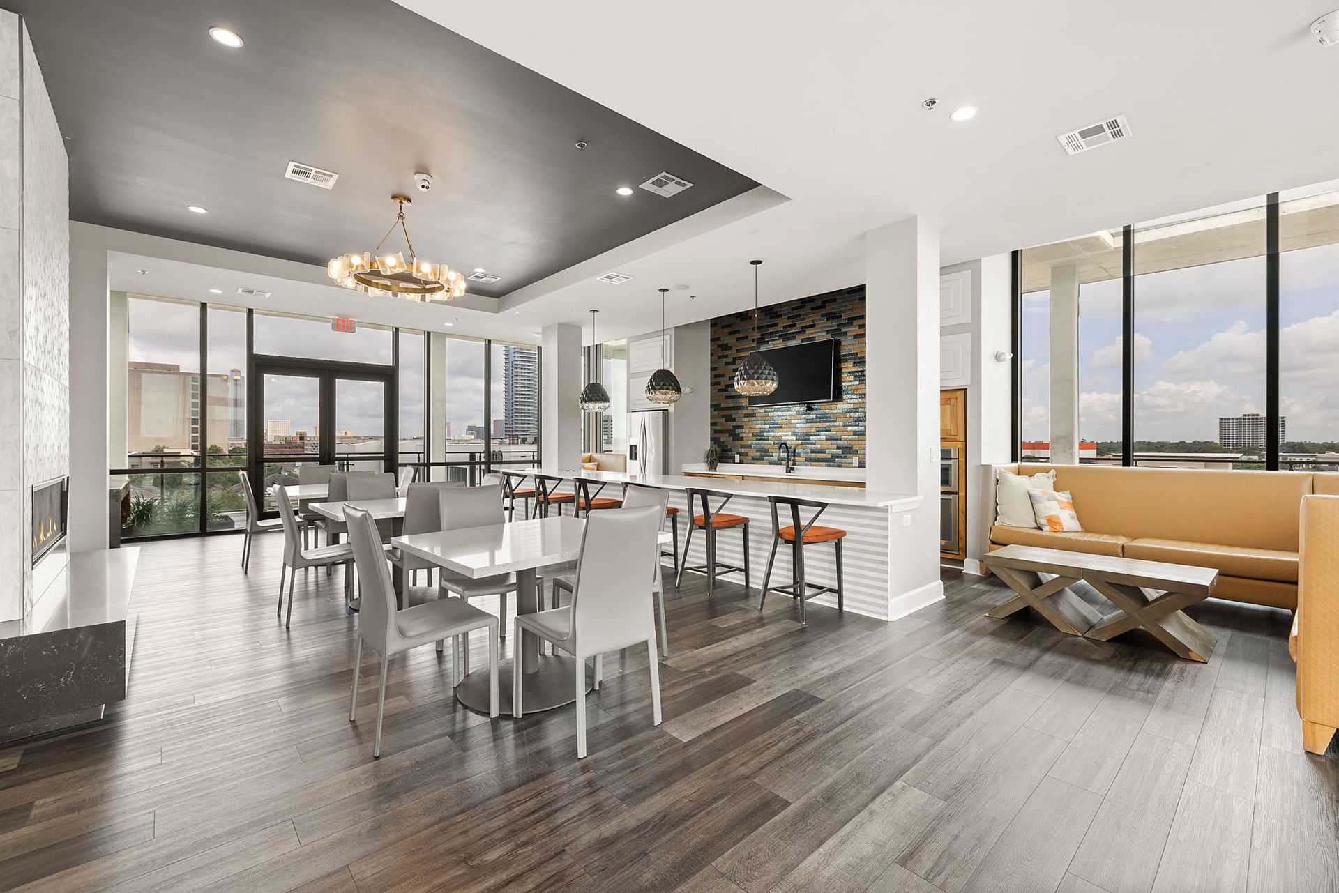 Modern open-concept kitchen and living area with white furniture, gray floors, and city views