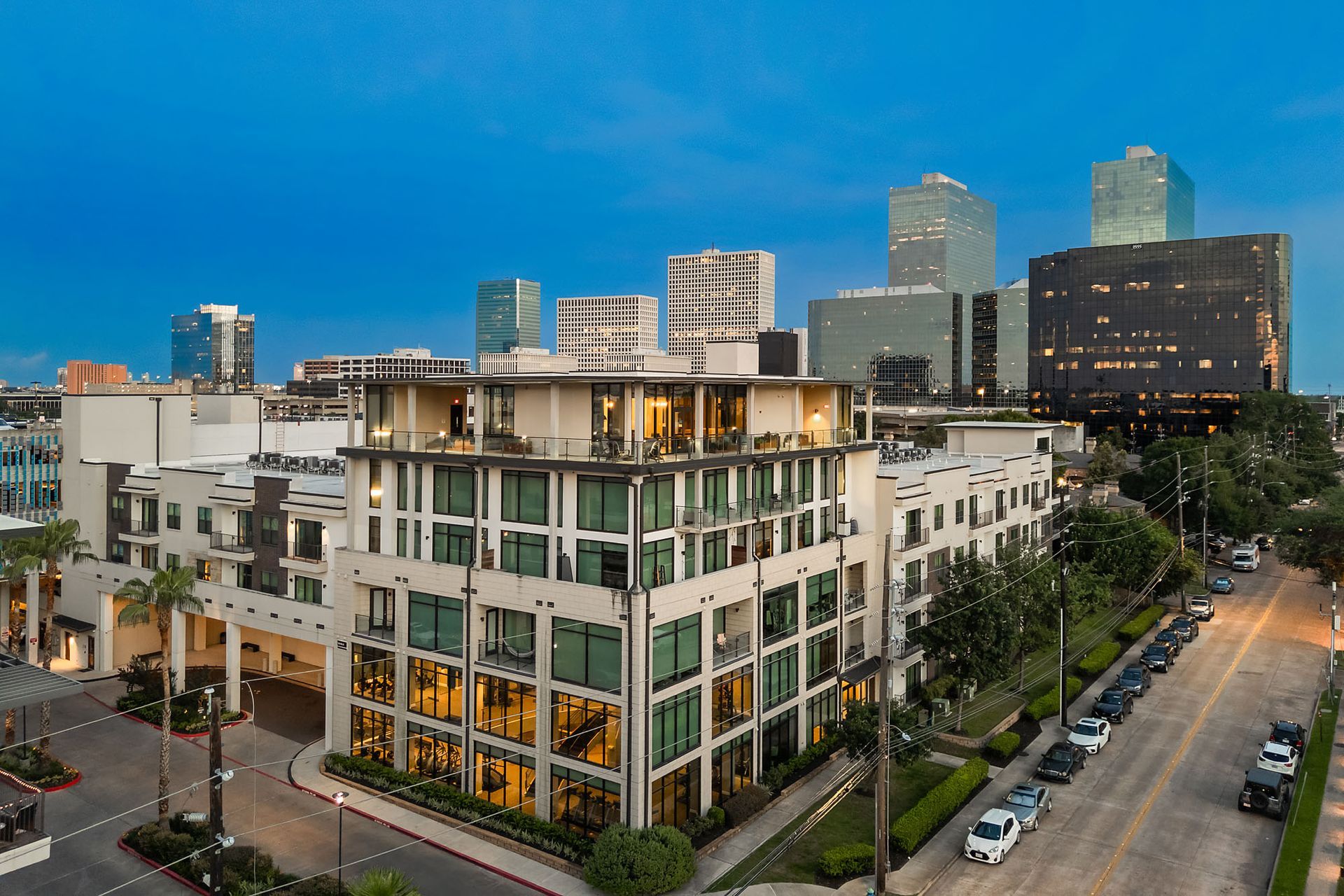 Modern apartment building at dusk with city skyline and lit windows