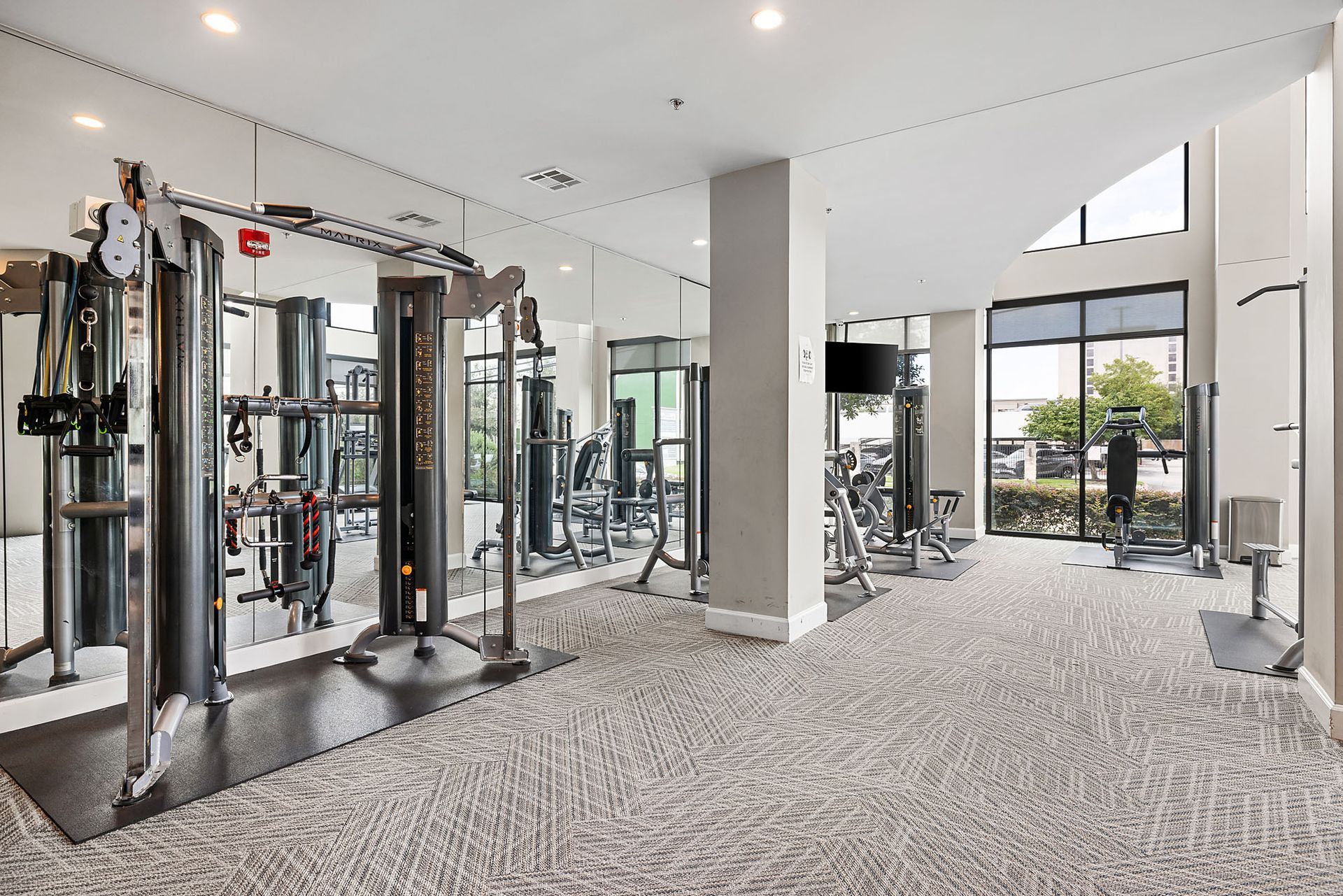 Bright modern gym interior with exercise machines, mirrors, and large windows