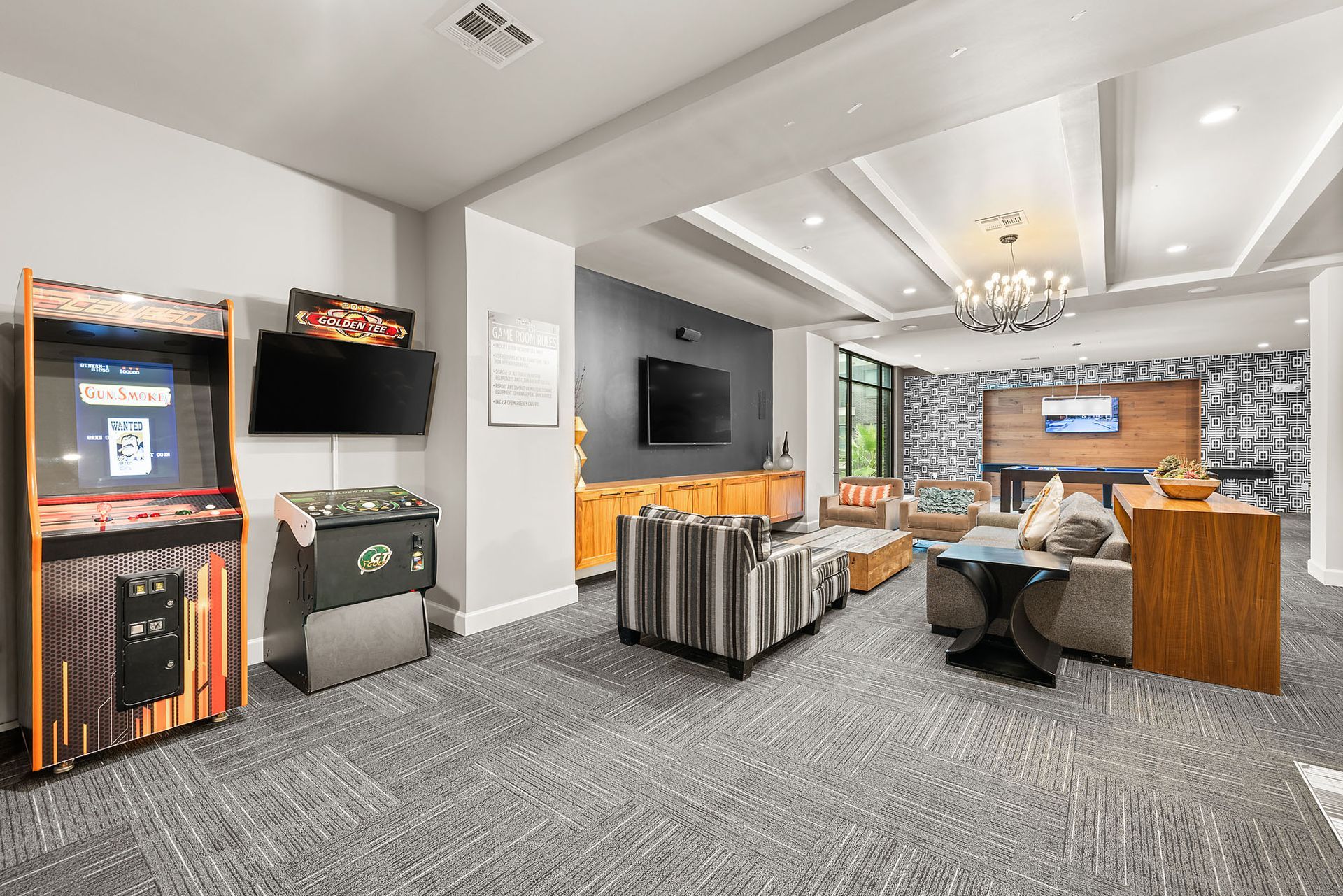 Modern living room with gray sofa, wood desk, TV, and stone accent wall in a bright open layout